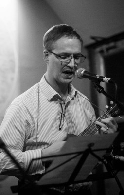 Robert playing a banjo and singing into a microphone